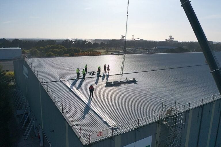 Commercial roofing team performing emergency roof repairs on a large industrial metal roof